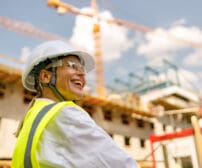 Professional female engineer in protective helmet against on construction background