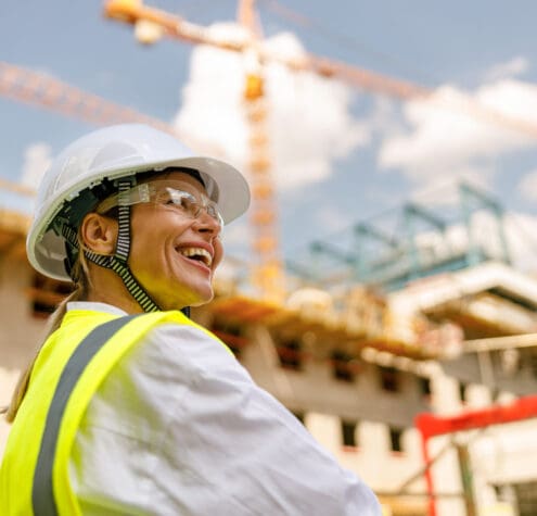 Professional female engineer in protective helmet against on construction background