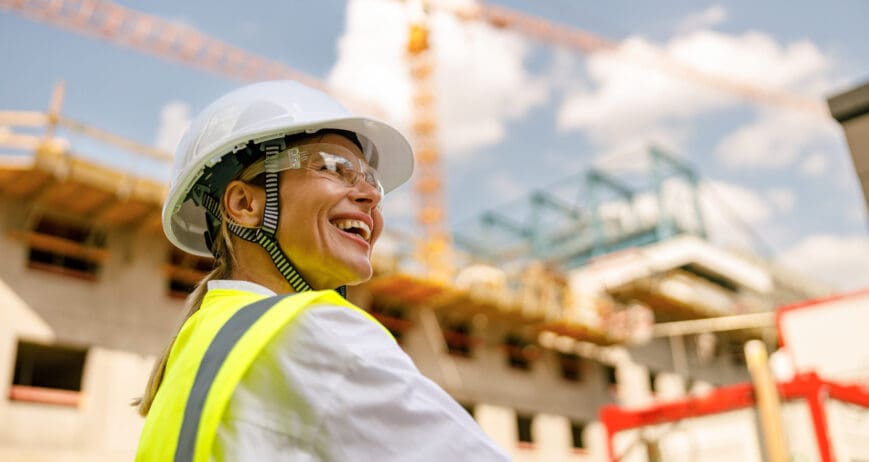 Professional female engineer in protective helmet against on construction background